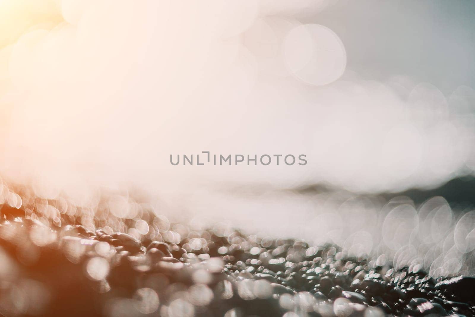 Blurred golden sea at sunset. The sun reflects and sparkles on the waves with bokeh, illuminating the golden sea. Holiday recreation concept. Abstract nautical summer ocean sunset nature background. by panophotograph