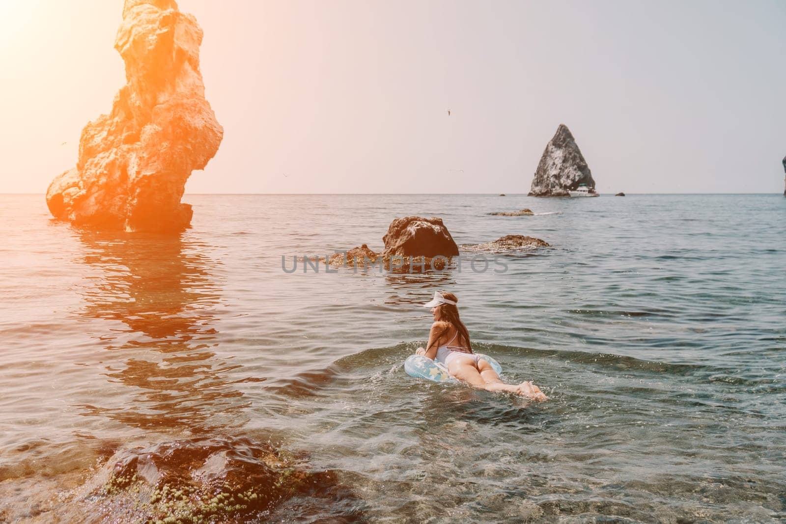 Woman summer sea. Happy woman swimming with inflatable donut on the beach in summer sunny day, surrounded by volcanic mountains. Summer vacation concept. by panophotograph