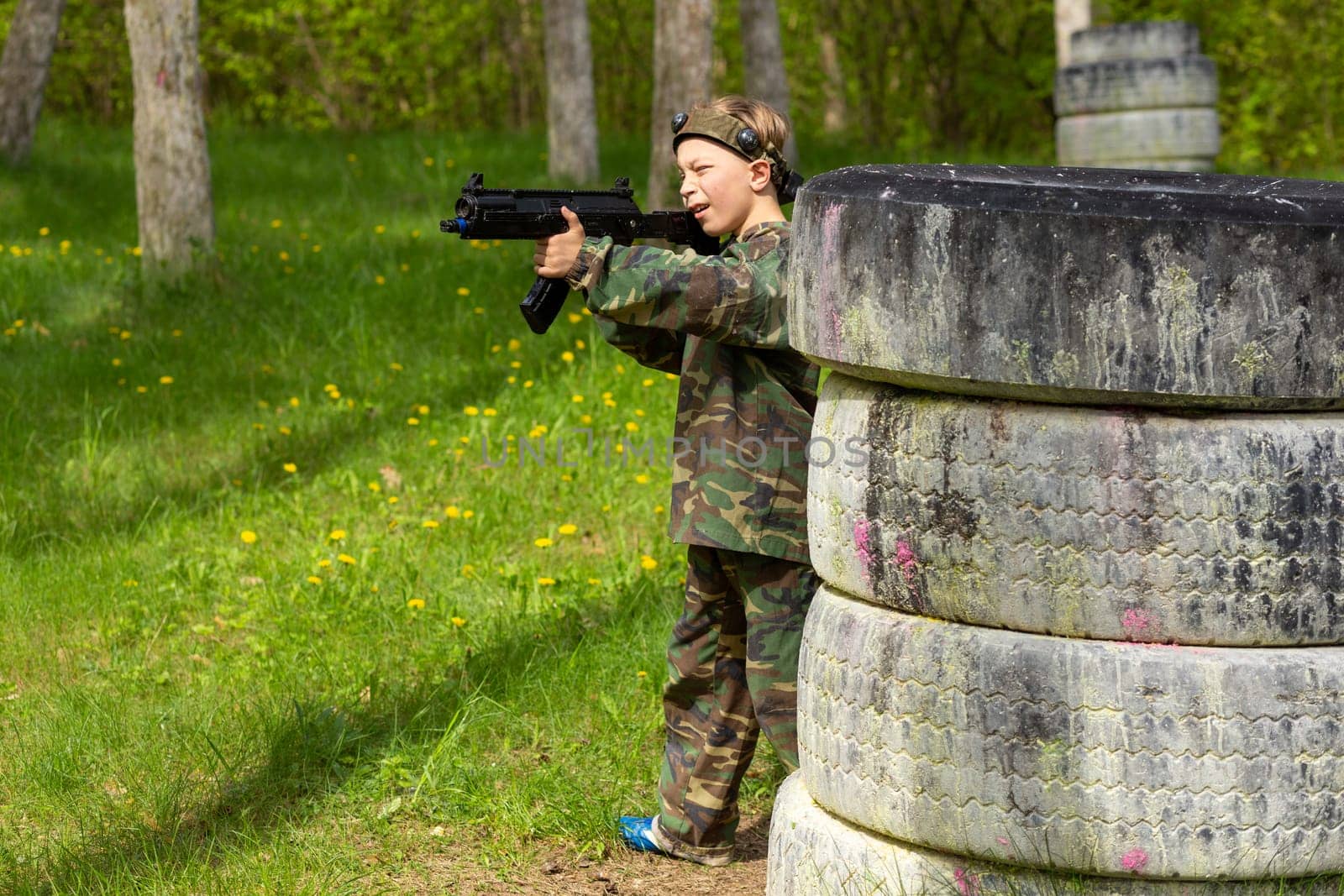 Boy weared in camouflage playing laser tag in special forest playground. Laser Tag is a command military tactical game using safe laser weapons and sensors that record hits.