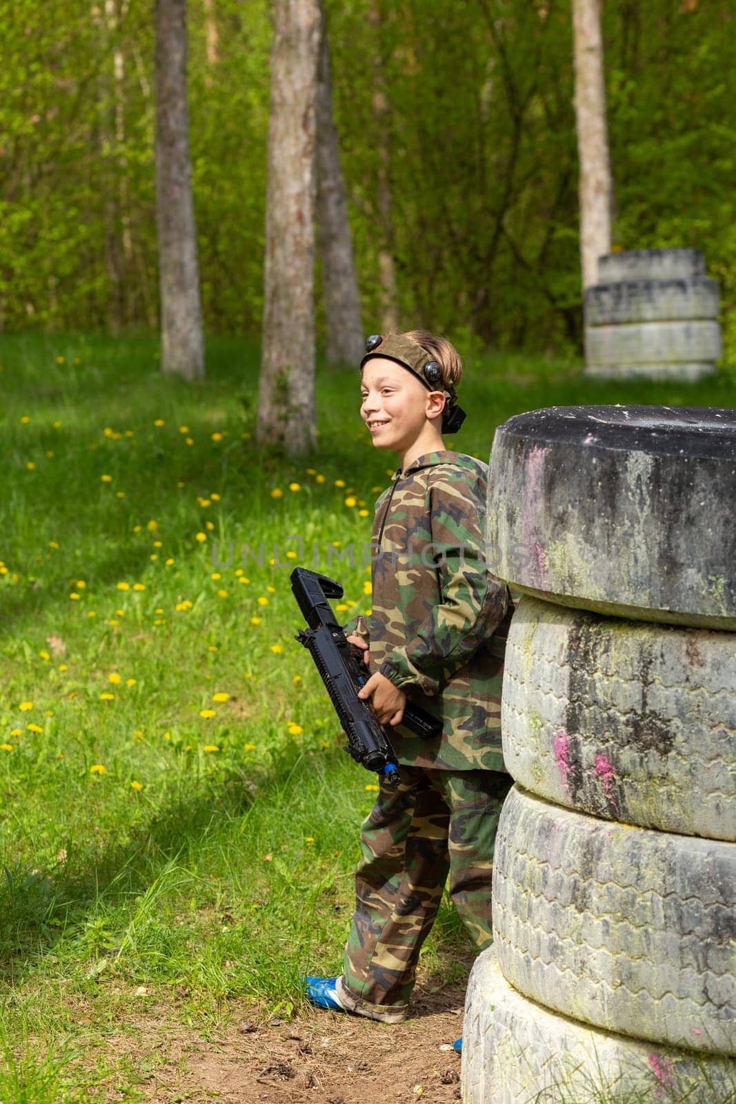 Boy weared in camouflage playing laser tag in special forest playground. Laser Tag is a command military tactical game using safe laser weapons and sensors that record hits.