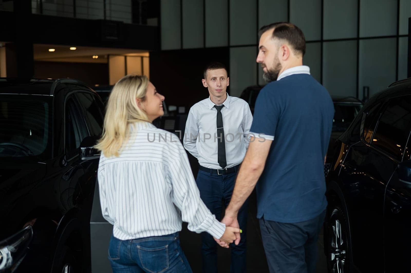 Happy caucasian couple choosing a new car in a car dealership