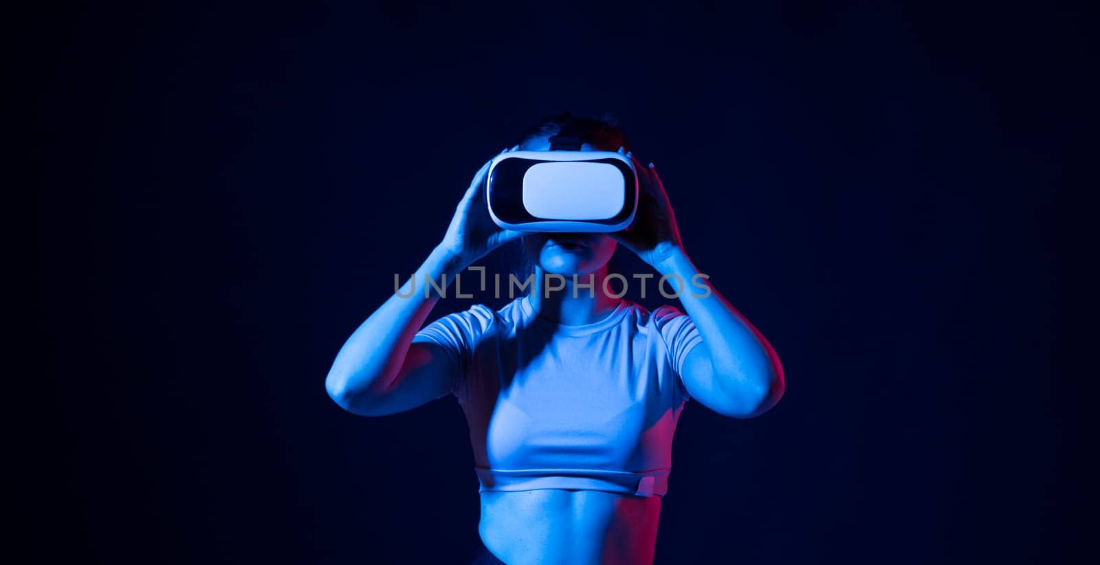 Woman enjoying a VR experience. Woman with VR headset touching invisible screen. Future technology concept