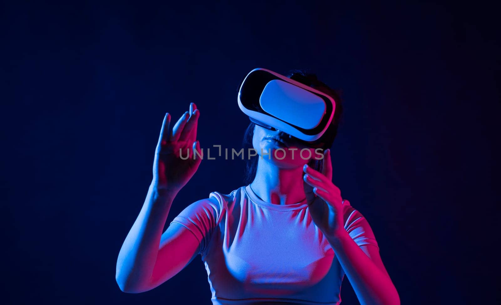 Amazed female in VR glasses headset interacting with network while having virtual reality experience. Future technology concept. Metaverse. by vovsht