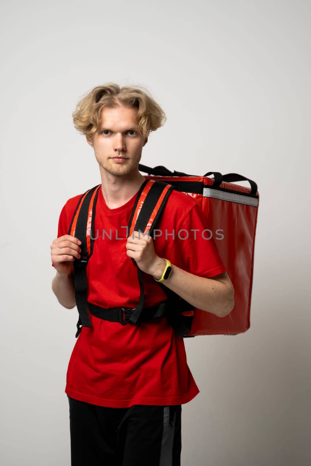 Courier delivers groceries home. Delivery man in red uniform with a thermal backpack isolated on a white background. Fast home delivery. Online order