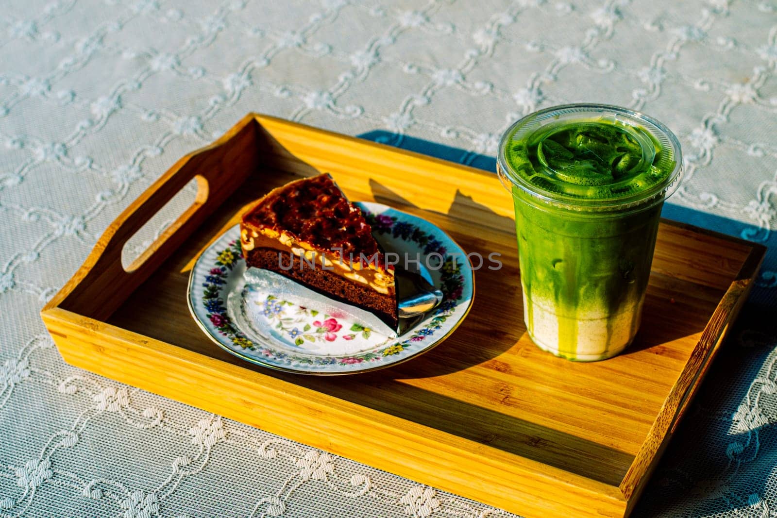 cake and Green tea Latte on outdoor wooden table in sunshine morning