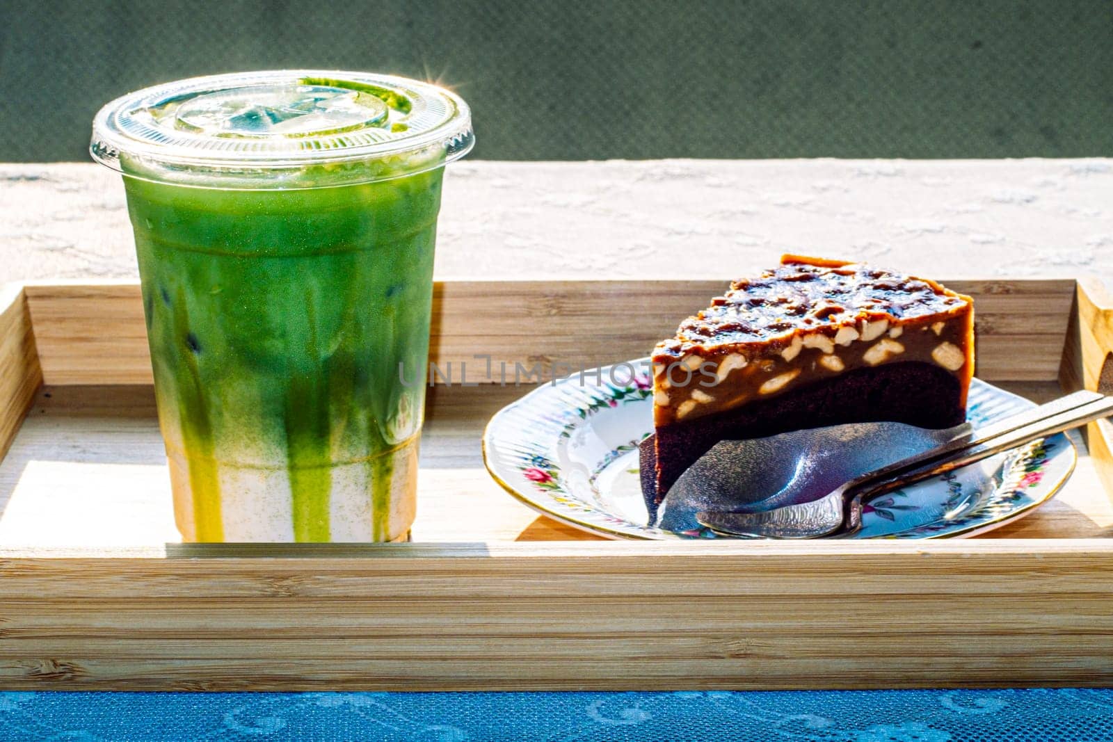cake and Green tea Latte on outdoor wooden table in sunshine morning