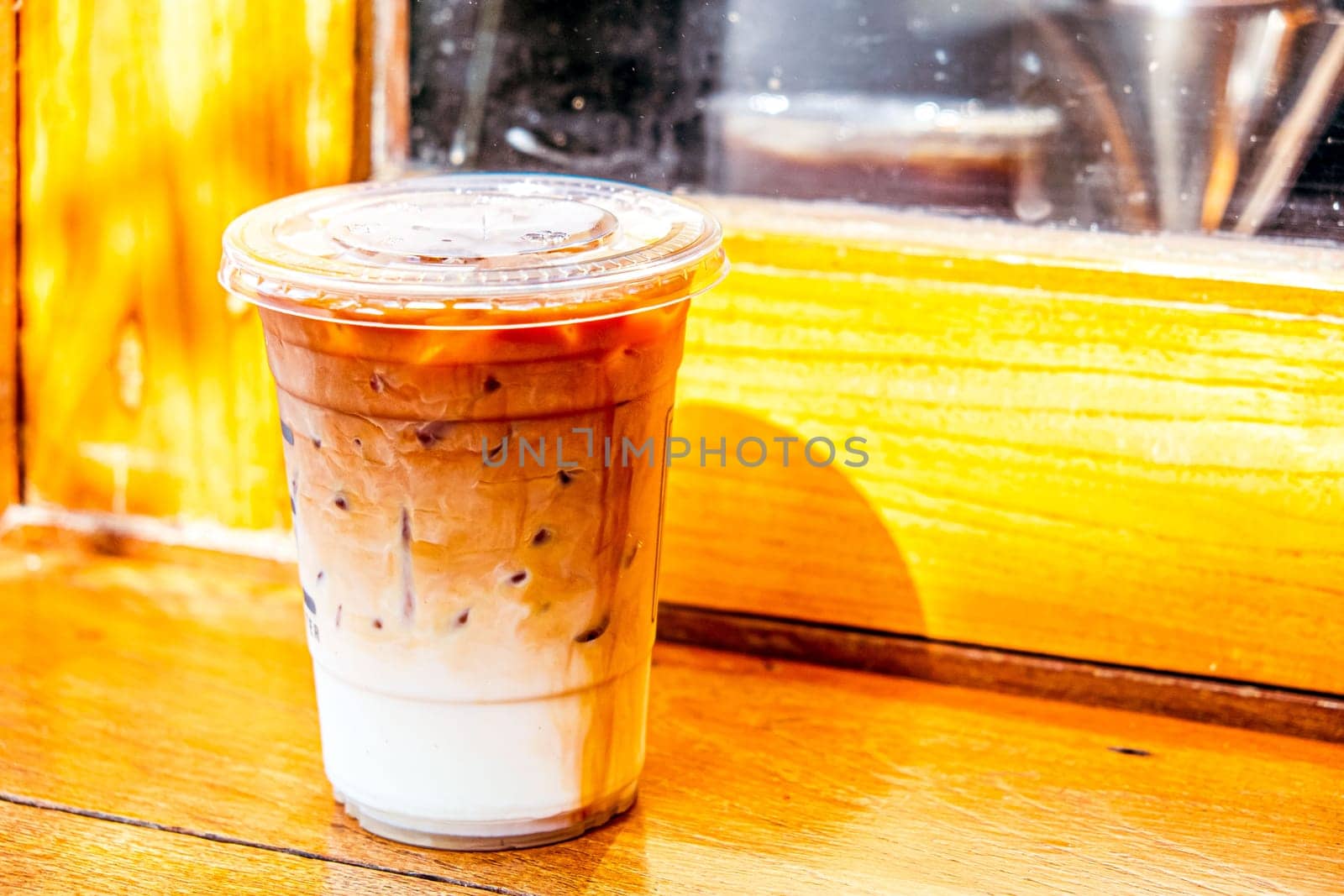 plastic glass of iced latte coffee with fesh milk on wood window