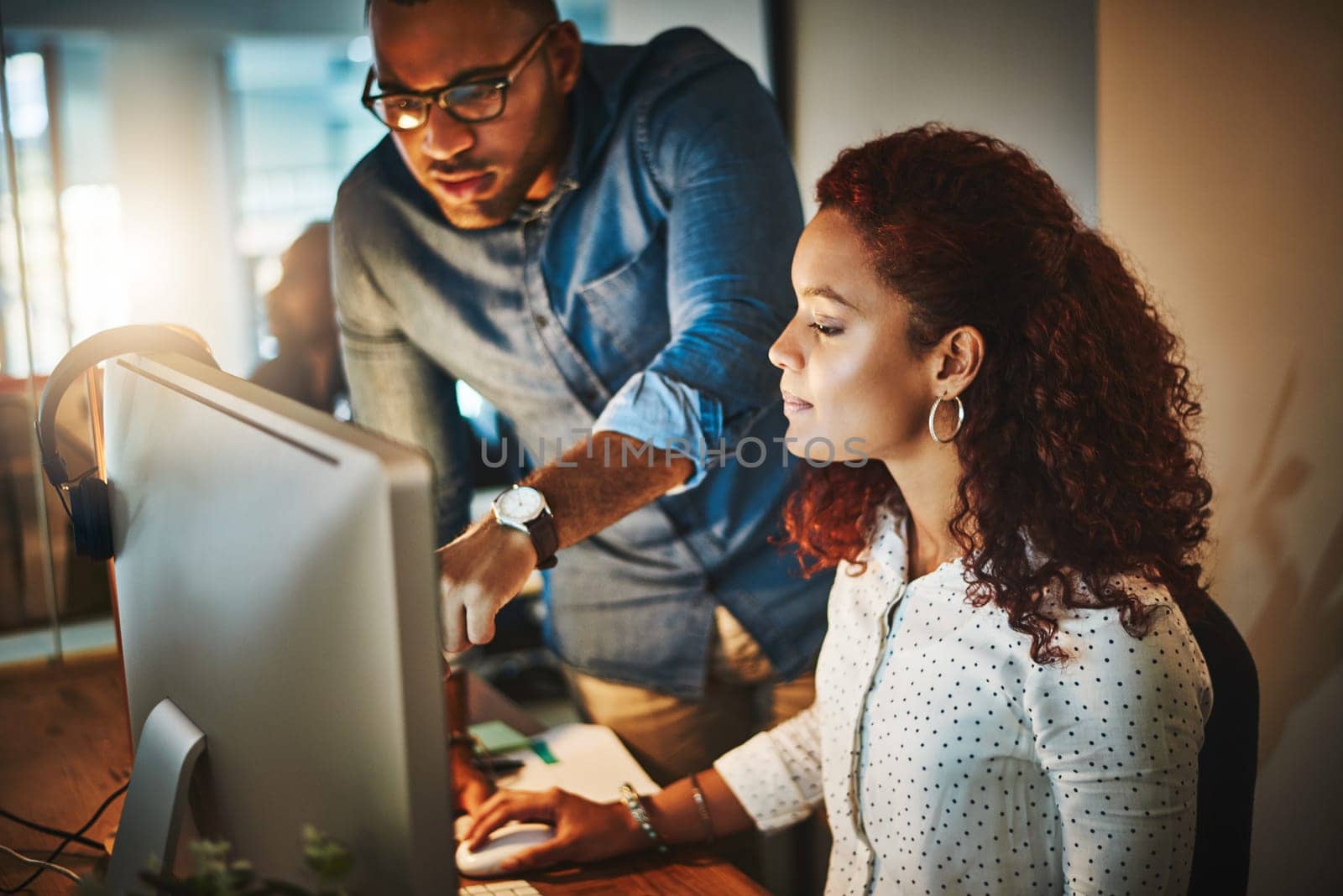 The experts in productivity. a young businessman and businesswoman using a computer together during a late night at work