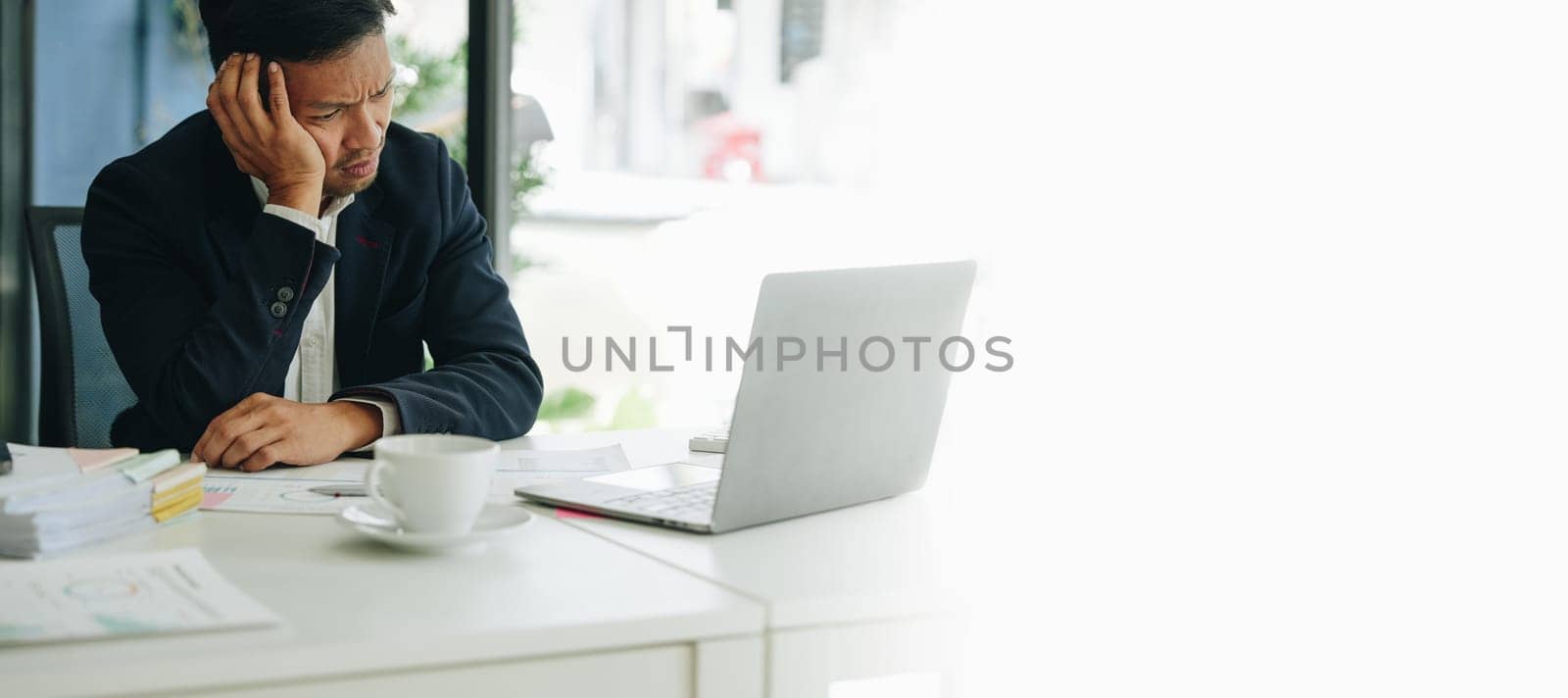 Portrait of business owner, man using computer and financial statements Anxious expression on expanding the market to increase the ability to invest in business. by Manastrong