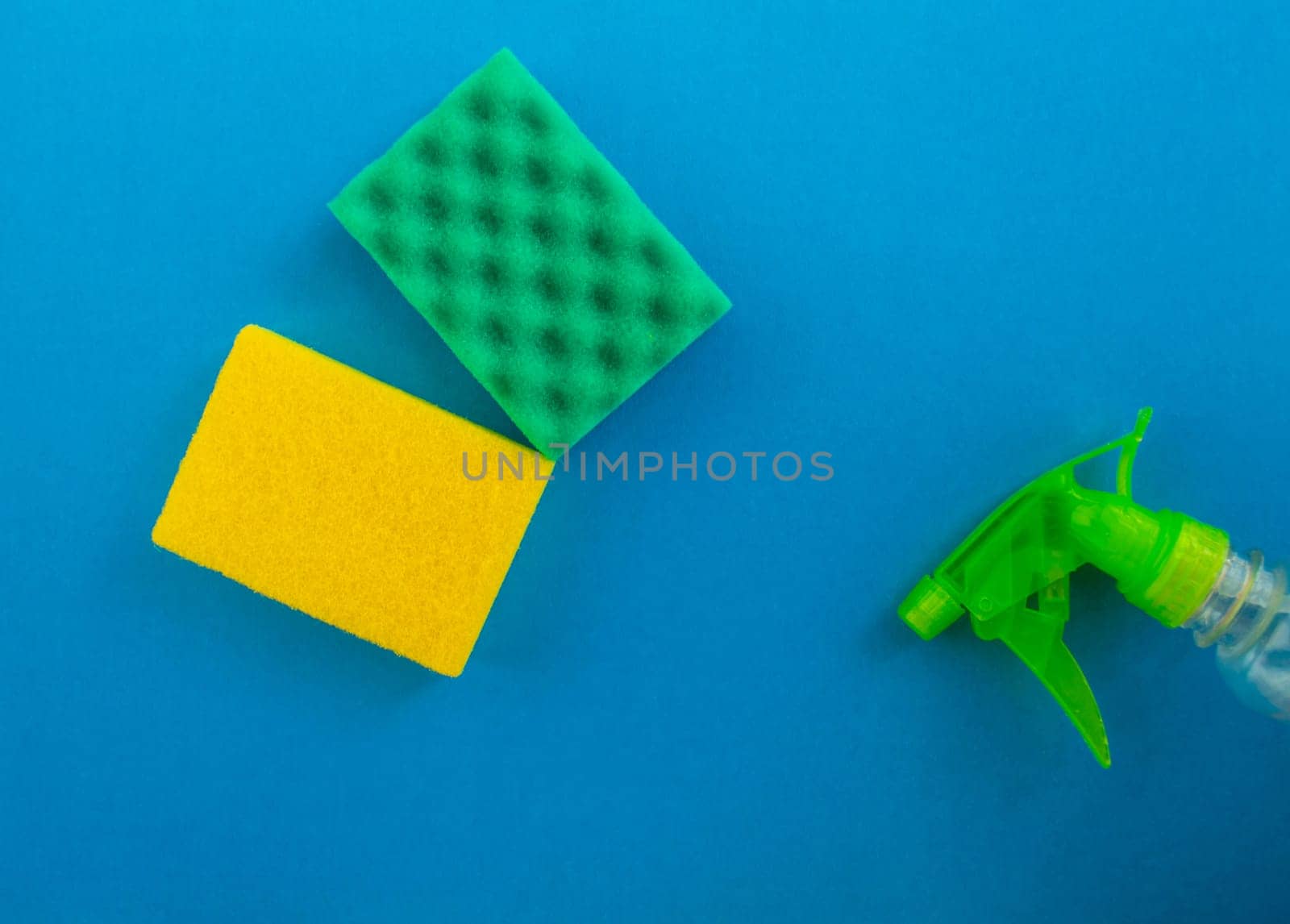 Cleaning. Flat lay sponges and cleaning product on a blue background. Cleaning supplies, top view.