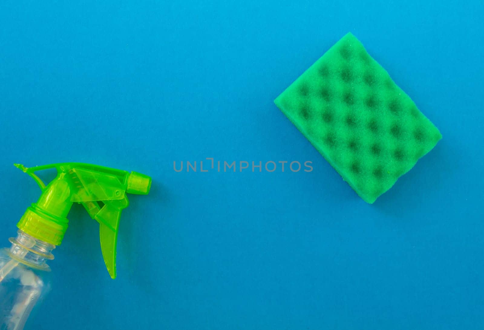 Cleaning. Flat lay sponge and cleaning product on a blue background. Cleaning supplies, top view.