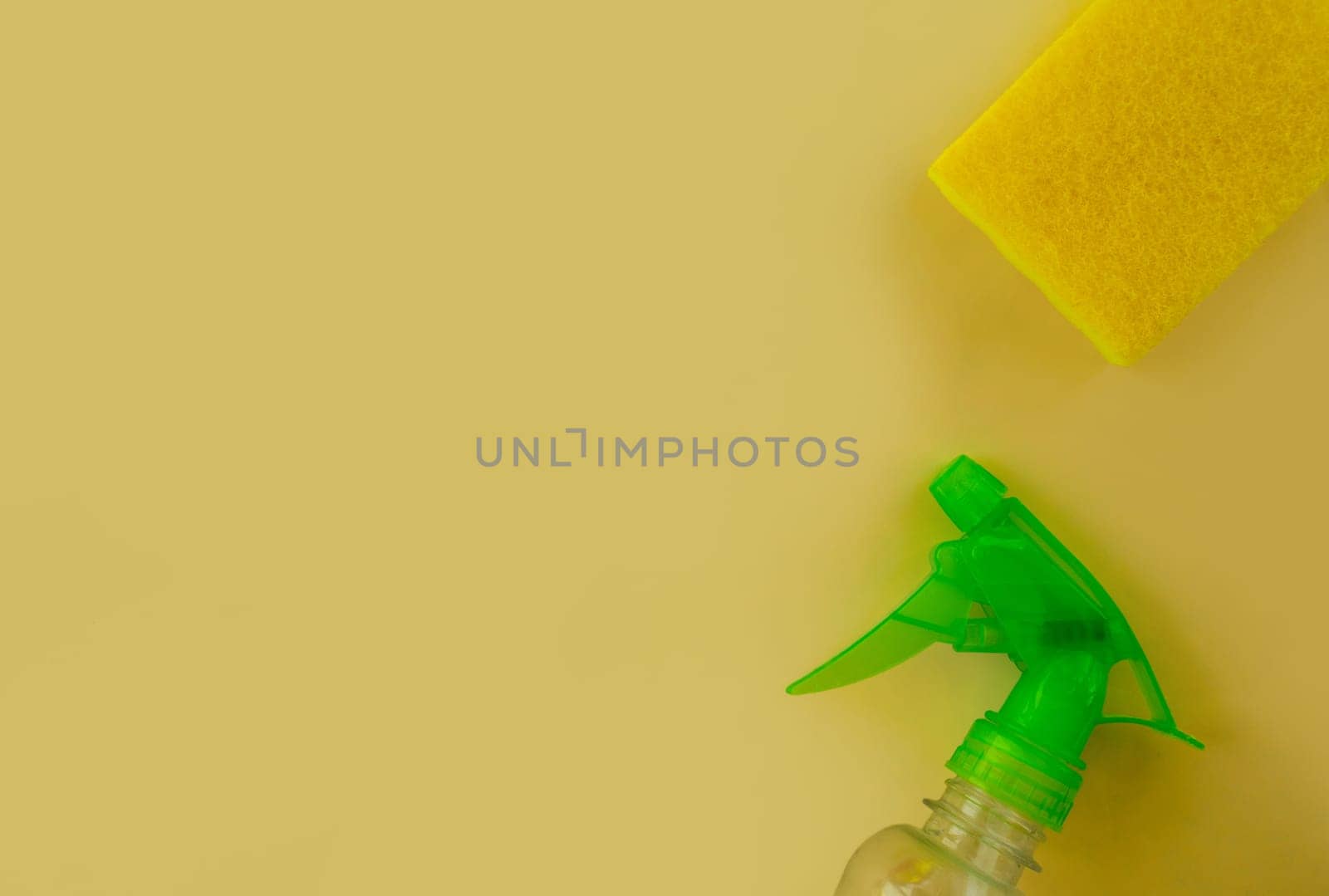Cleaning. Flat lay Bottle with cleaning product, sponge against yellow background. Cleaning supplies, top view.
