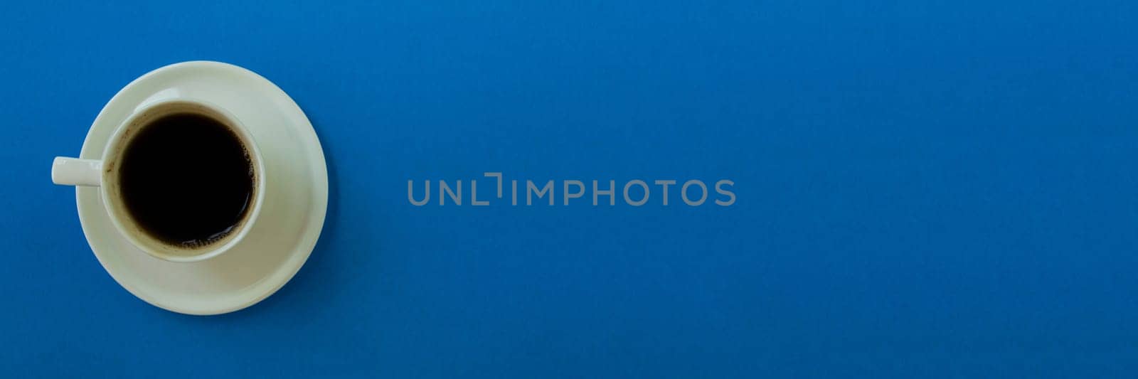 Banner.  Cup of coffee on a blue background. Cup of coffee with a saucer on a blue background, top view.