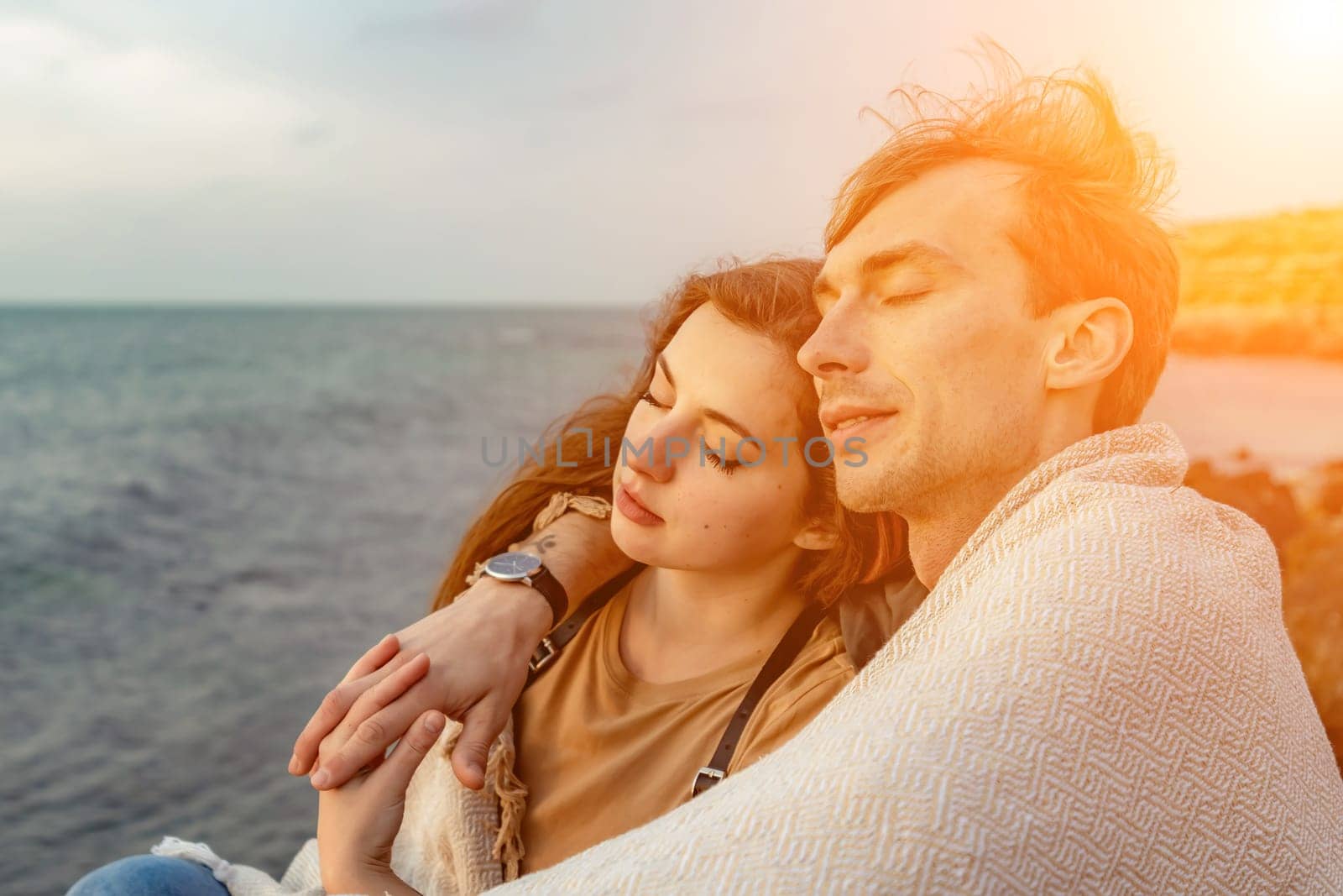 Portraits of lovers, romantic couple of lovers hugging, kissing, touching, eye contact at sunset, sunrise against the background of the sea, sun, clouds in fiery red, orange colors by Matiunina