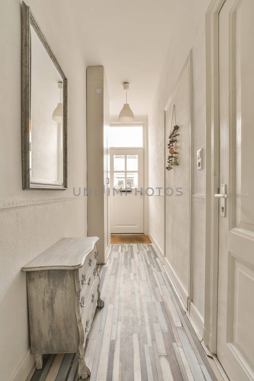 a long hallway with a dresser and a door by casamedia
