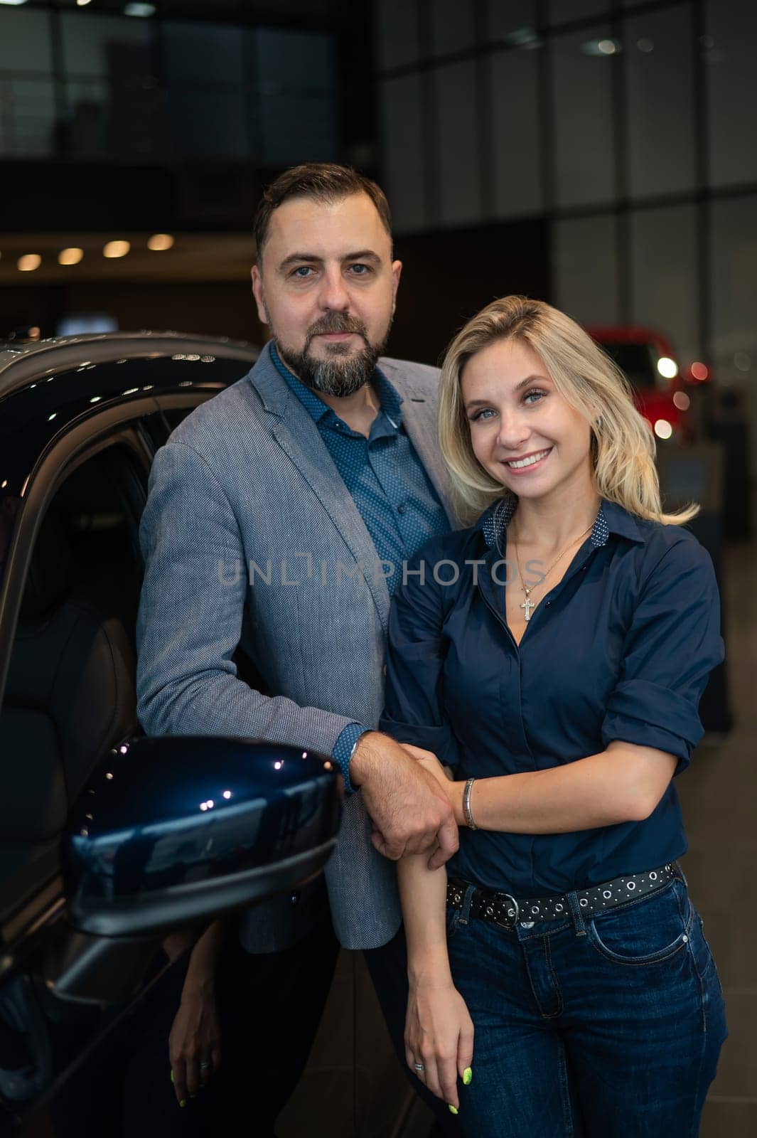 Portrait of a happy married couple in a car showroom. by mrwed54