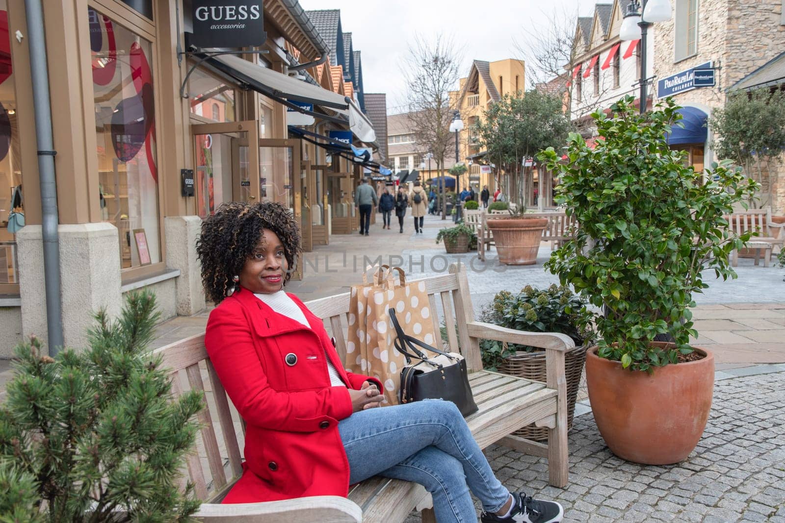 beautiful african american woman with big shopping bags relaxing after shopping on outdoor bench, Maasmechelen,Belgium,February 17,2023, High quality photo