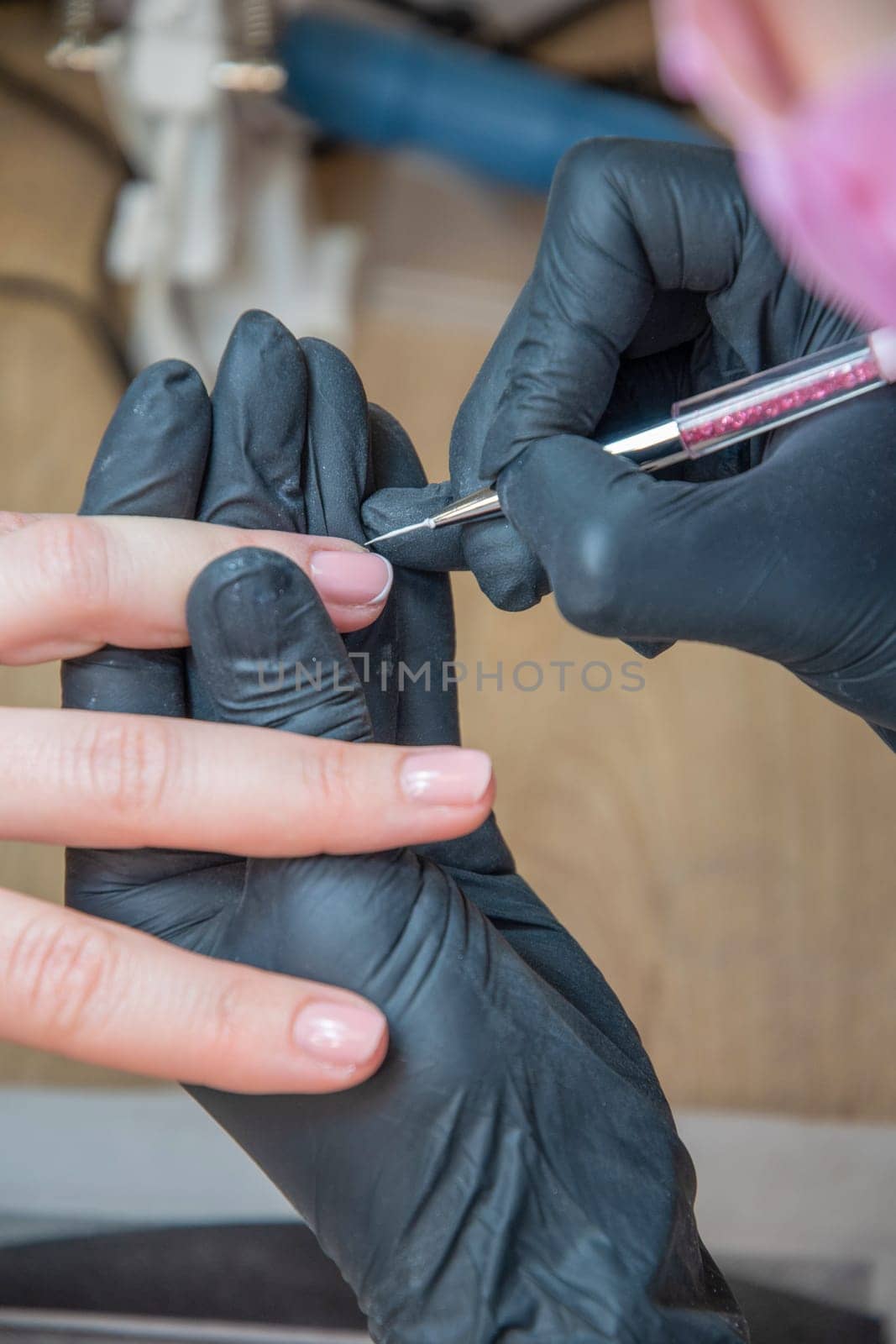 A master manicurist makes a drawing french manicure nails using white varnish and a thin brush, Manicure process, High quality photo
