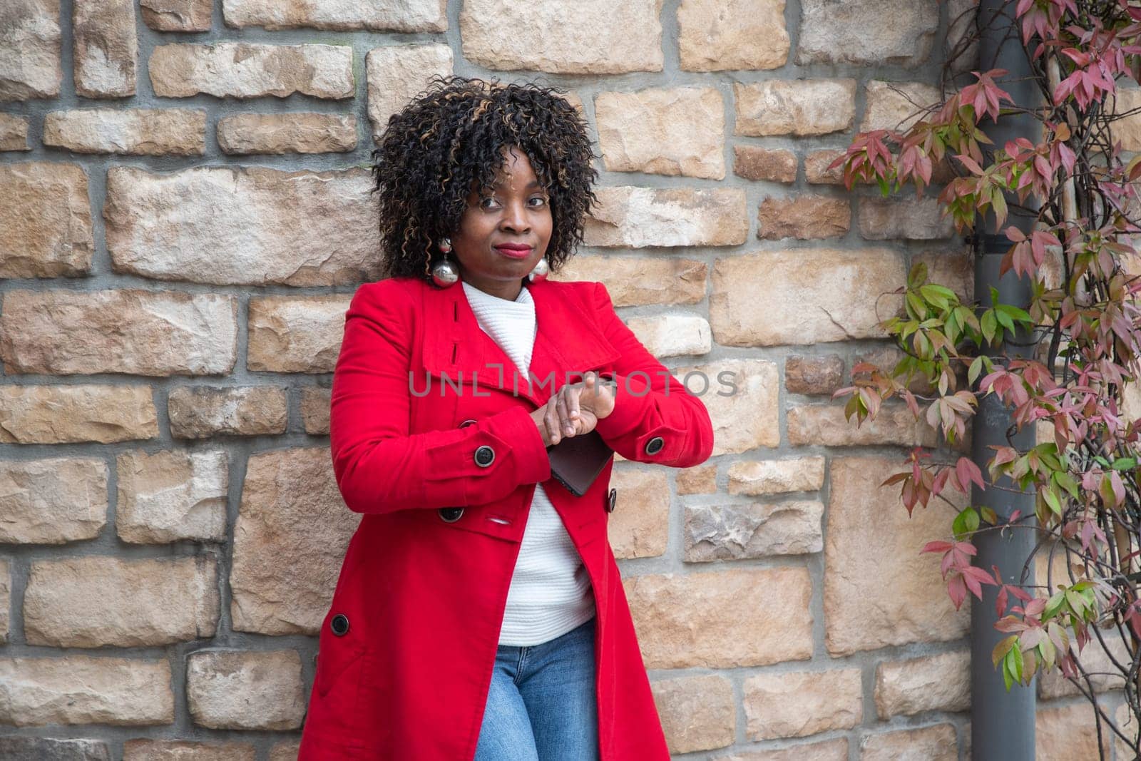 serious african american woman looks impatiently at her wrist watch near house while waiting for her husband, High quality photo