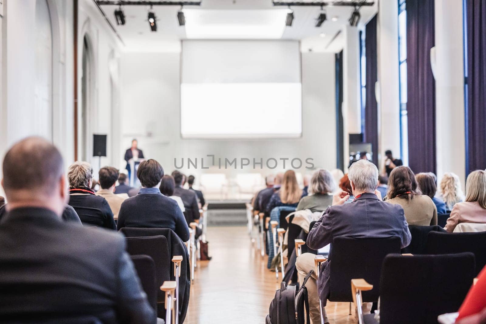 Speaker giving a talk in conference hall at business event. Rear view of unrecognizable people in audience at the conference hall. Business and entrepreneurship concept. by kasto