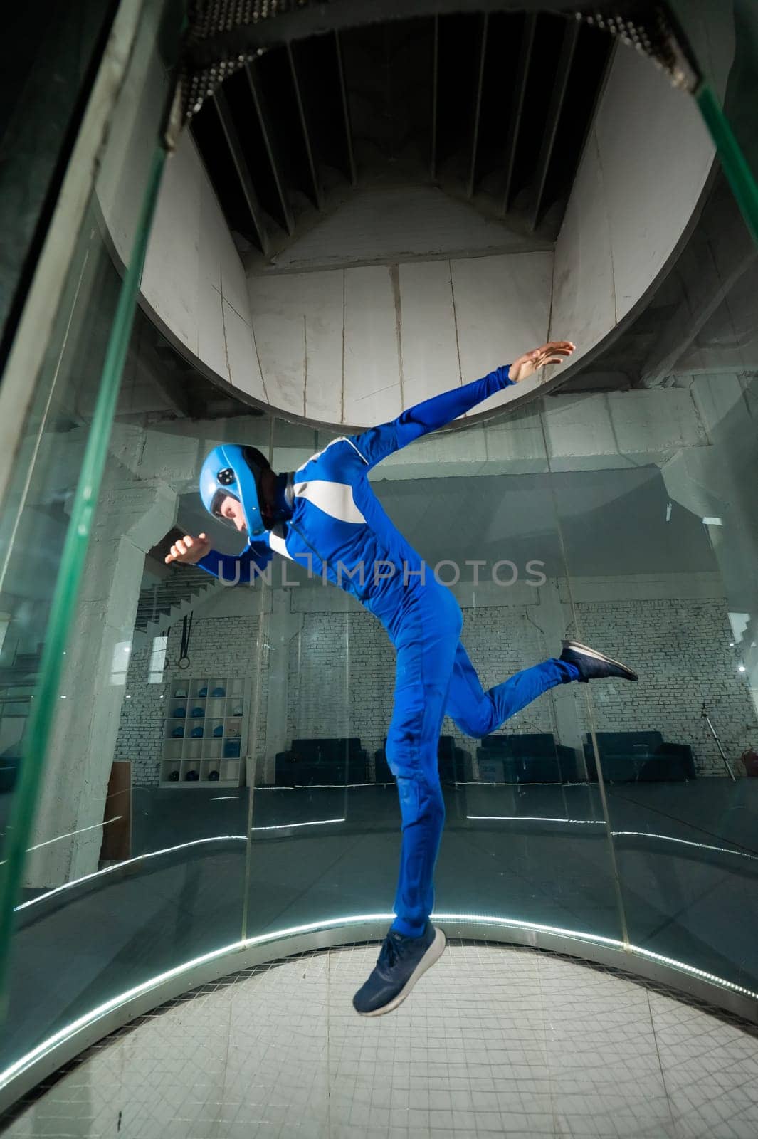A man in overalls and a protective helmet enjoys flying in a wind tunnel. Free fall simulator.