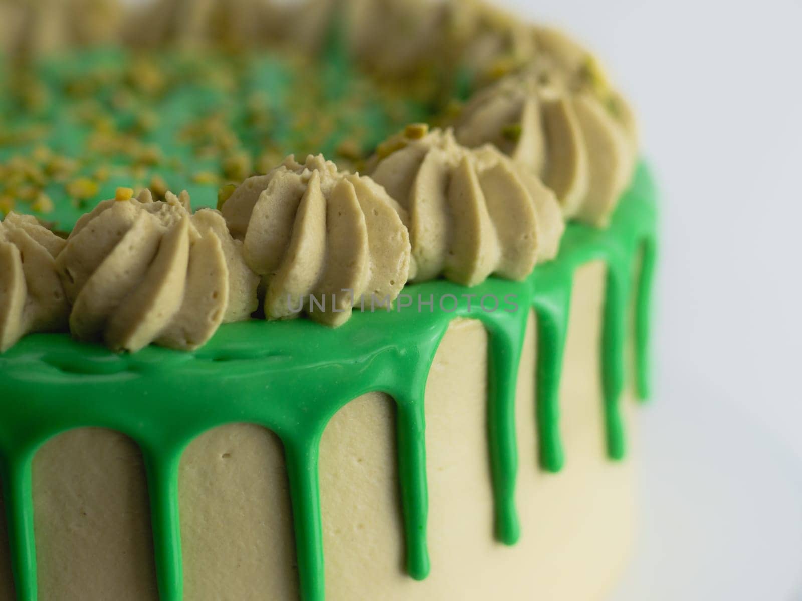 studio shot of green pistachio frosted dripped icing cup cake