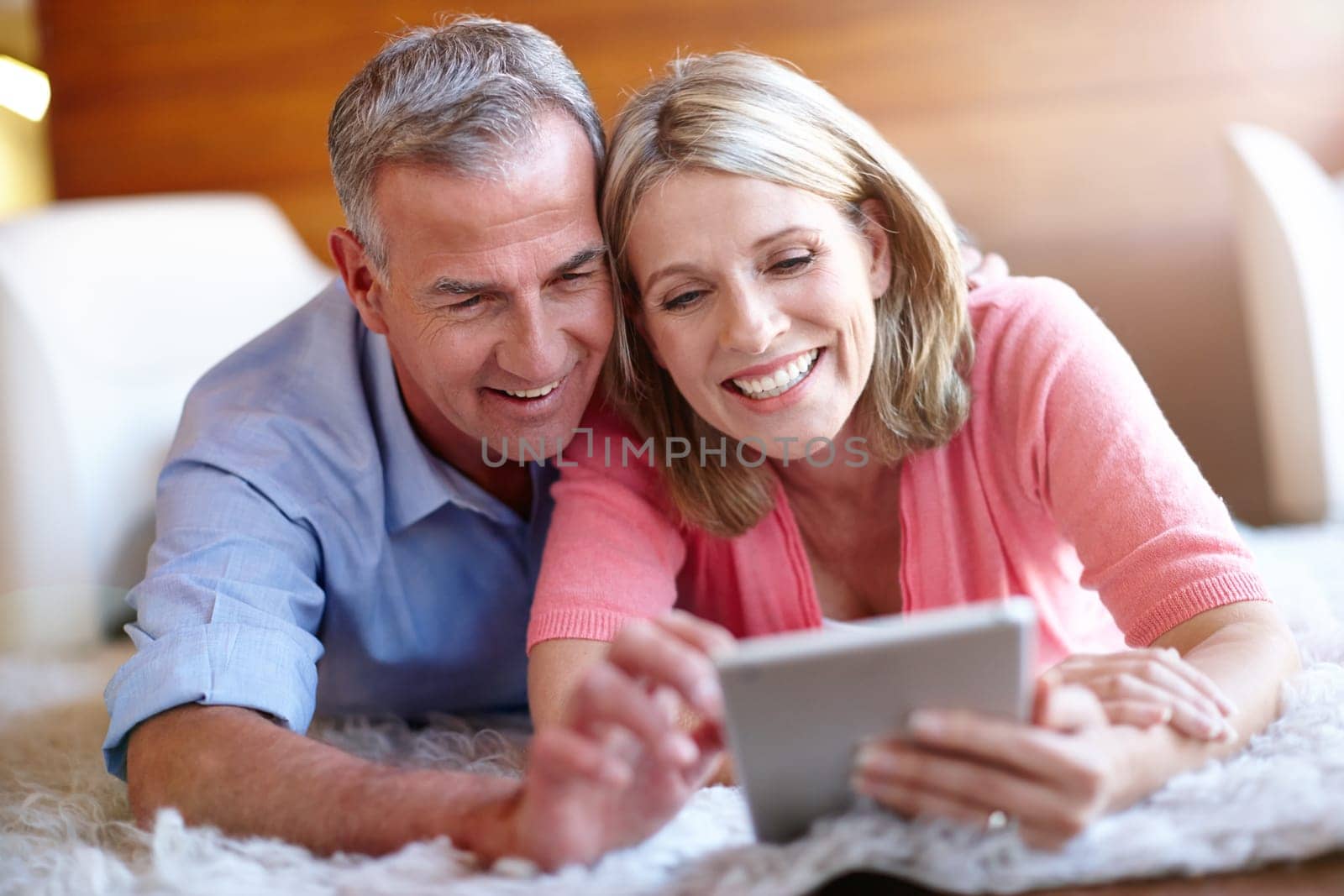 Technology brings them closer. a loving husband and wife using a digital tablet together at home. by YuriArcurs