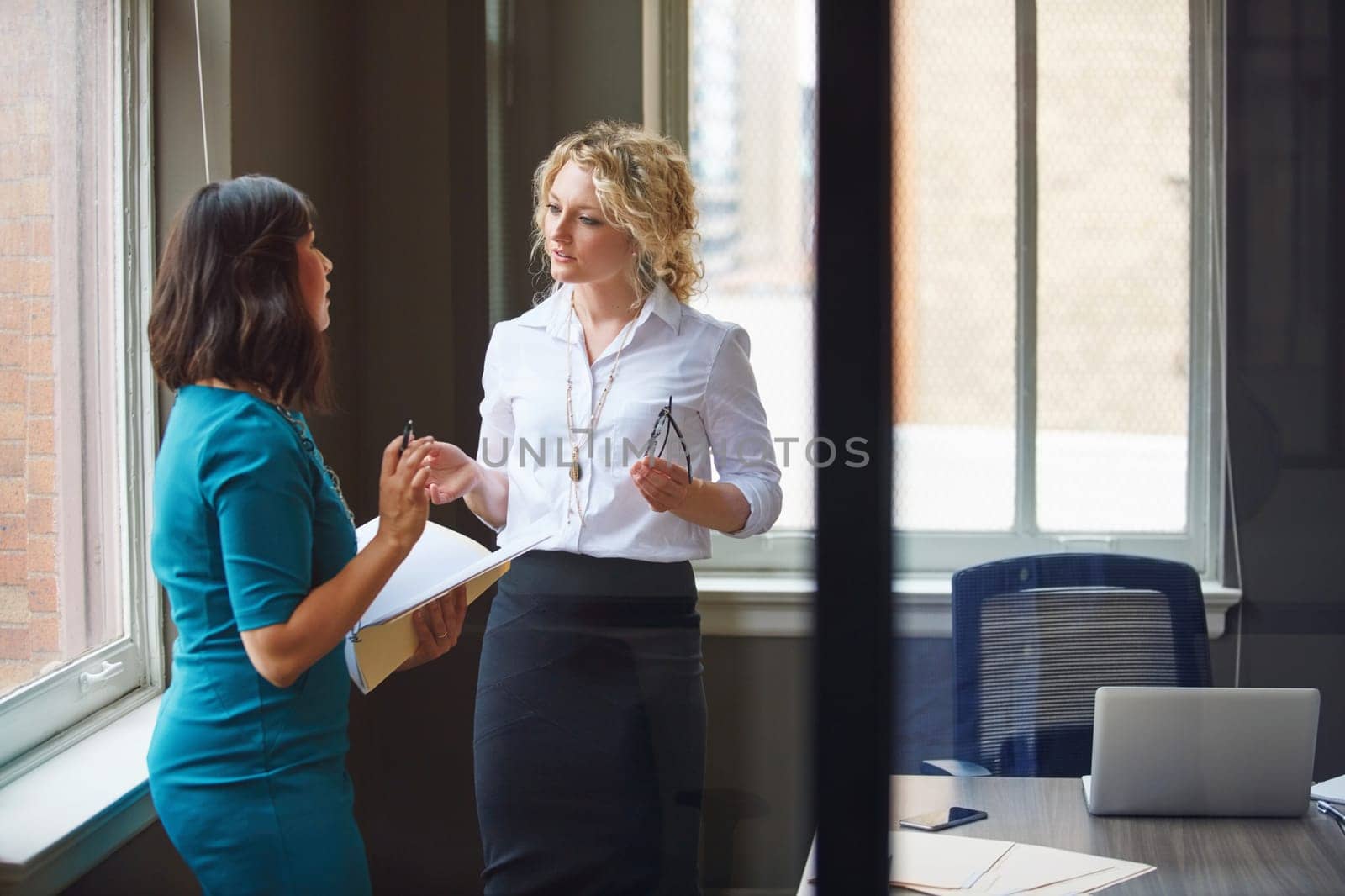 Effective communication makes for a productive team. two businesswomen having a discussion in an office. by YuriArcurs