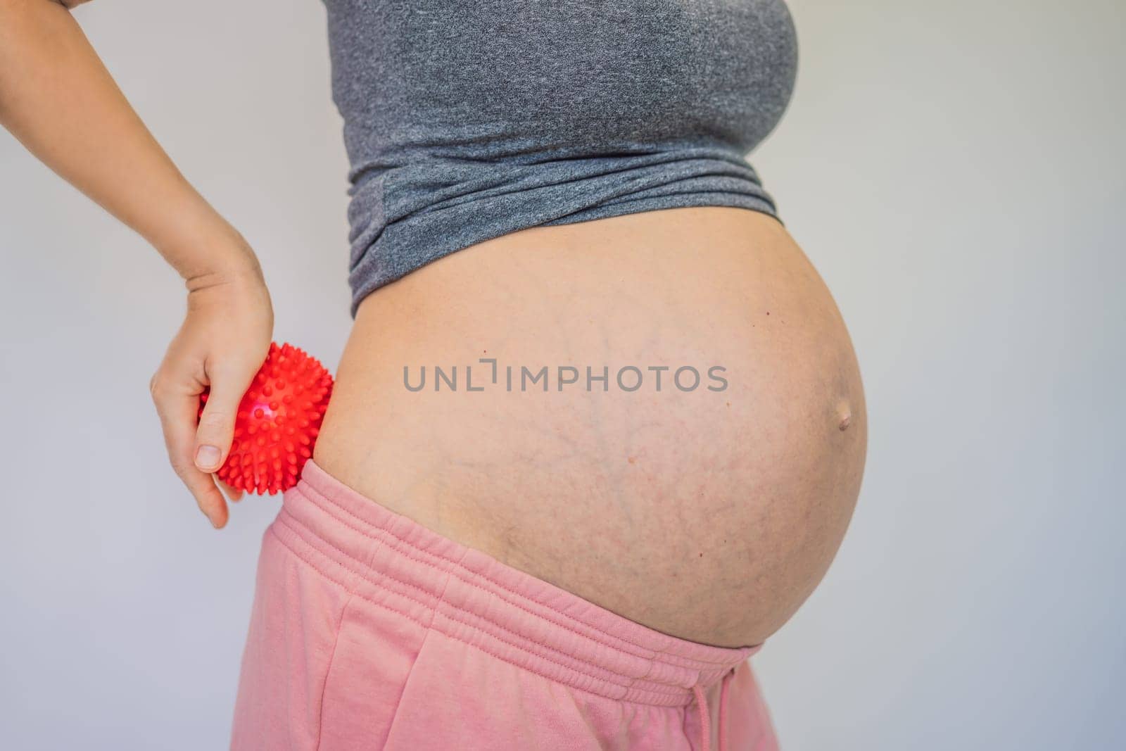 Self-massage with a massager for a pregnant woman.