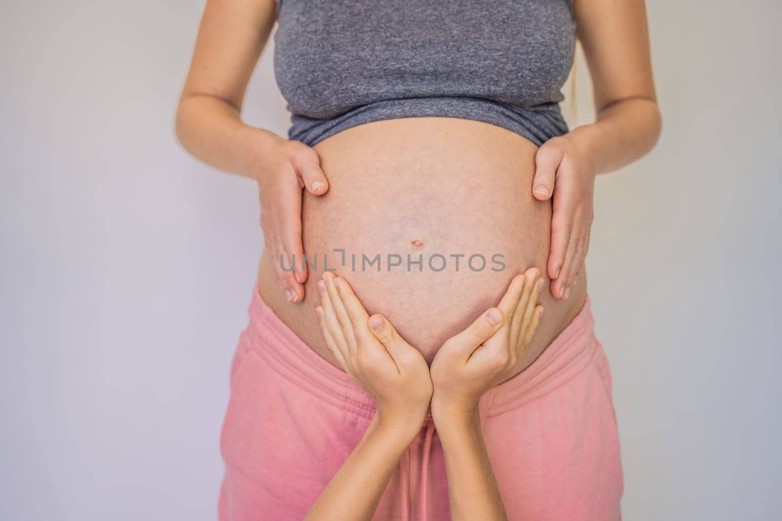 Young beautiful pregnant woman and eldest son. The cute boy put his hands on his mother's belly. Expecting a baby in the family concept. Preparing an older child for a younger one.