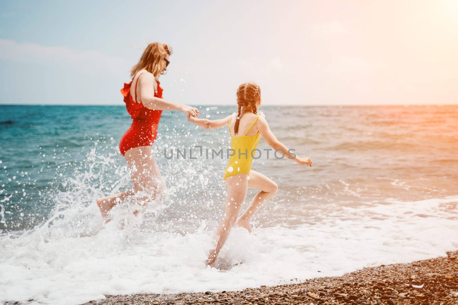 Happy loving family mother and daughter having fun together on the beach. Mum playing with her kid in holiday vacation next to the ocean - Family lifestyle and love concept by panophotograph