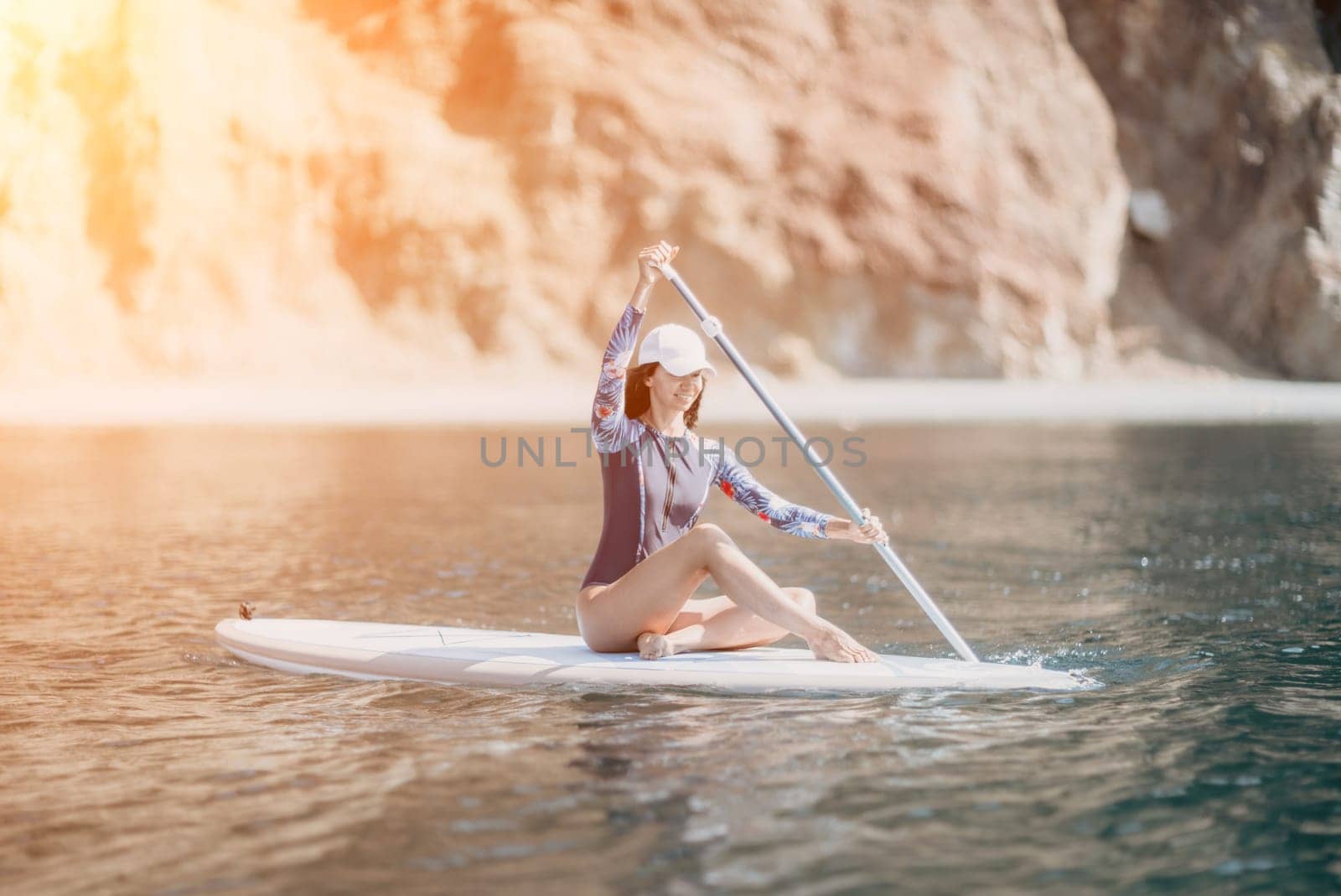 Woman sup yoga. Middle age sporty woman practising yoga pilates on paddle sup surfboard. Female stretching doing workout on sea water. Modern individual hipster outdoor summer sport activity