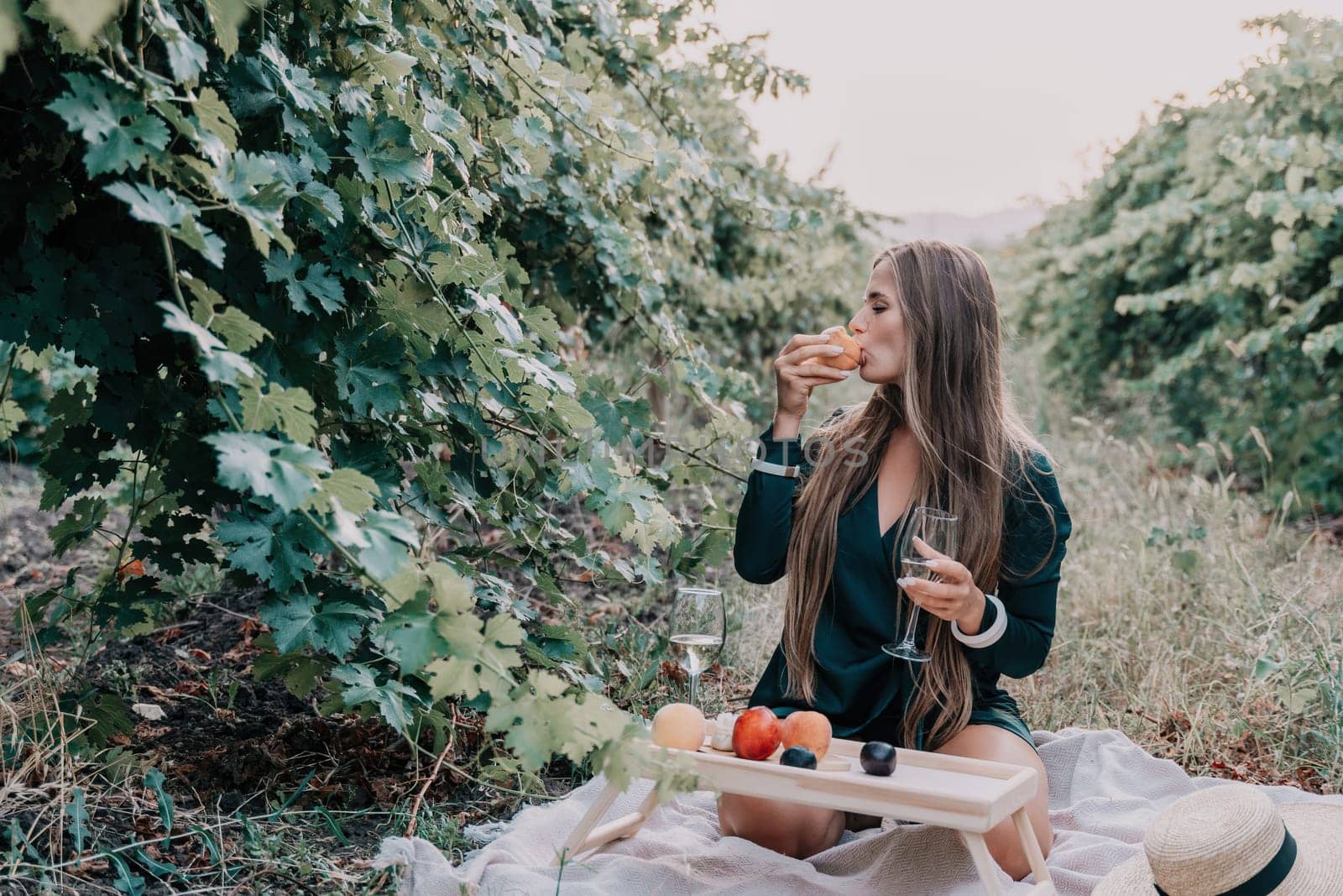 Woman picnic vineyard. Happy woman with a glass of wine at a picnic in the vineyard, wine tasting at sunset and open nature in the summer. Romantic dinner, fruit and wine. by panophotograph