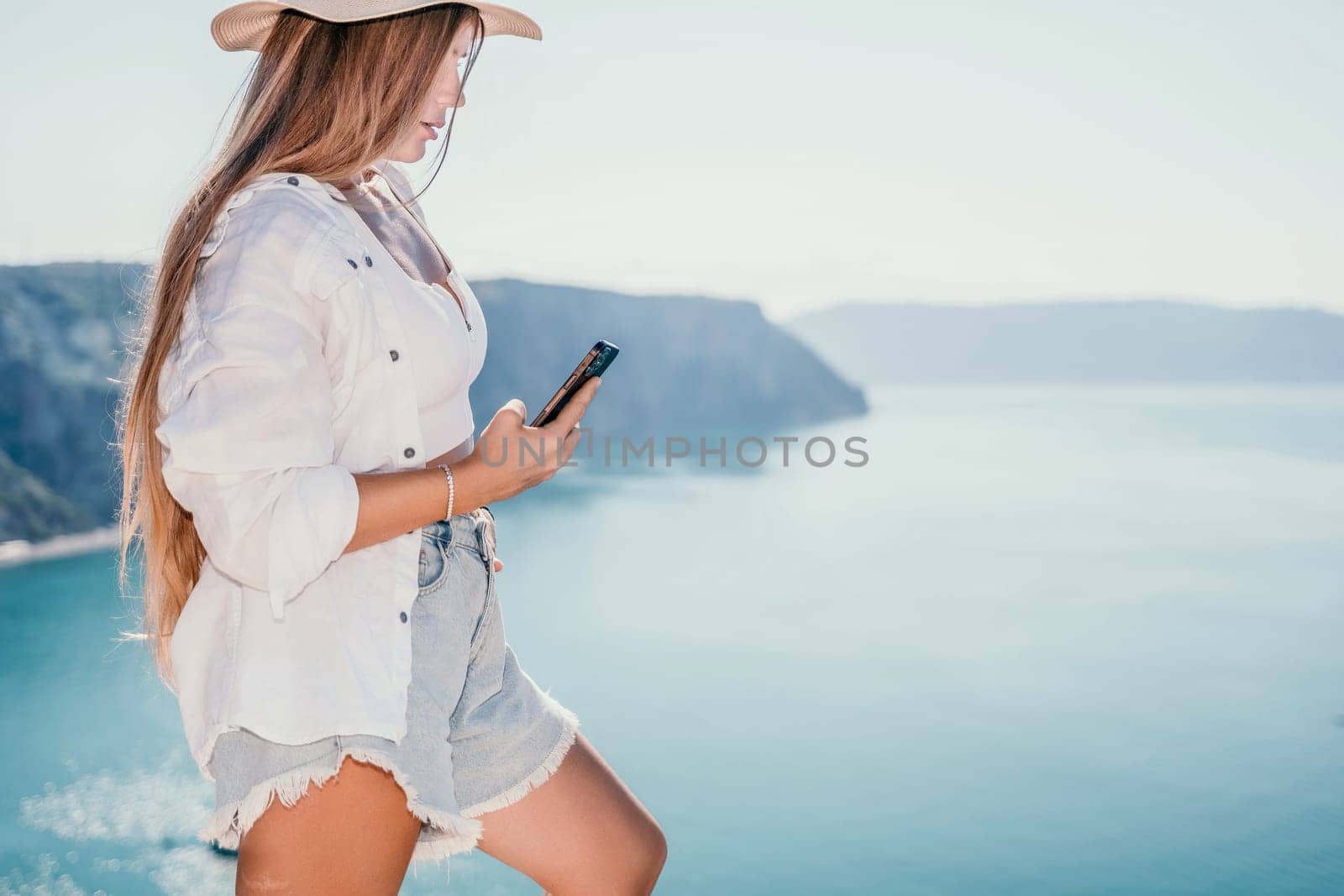 Digital nomad, Business woman working on laptop by the sea. Pretty lady typing on computer by the sea at sunset, makes a business transaction online from a distance. Freelance remote work on vacation