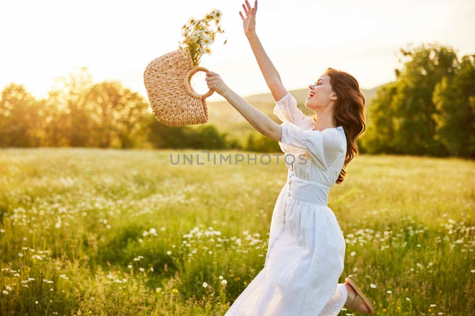 happy woman in a long light dress fool in the field with a wicker basket in her hands by Vichizh