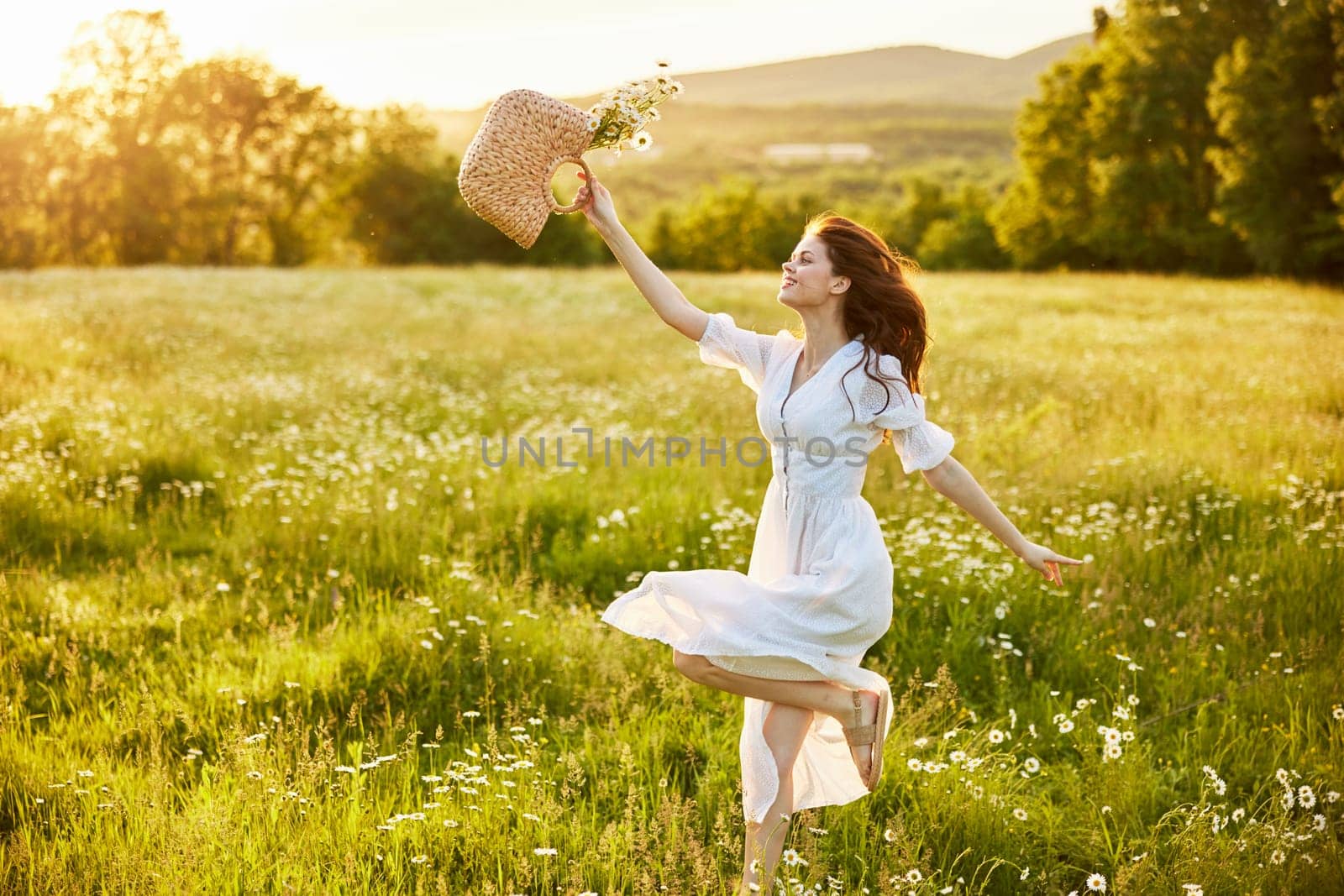 a woman in a light, long dress jumps in a field with a basket of daisies in her hands by Vichizh