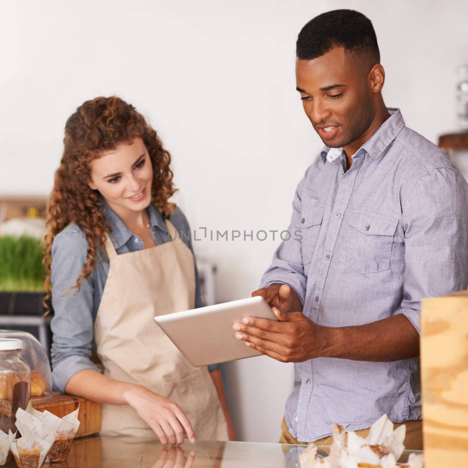 Tablet, cafe owner and teamwork of people talking, discussion and manage orders. Waiters, black man and woman in restaurant with technology for inventory, stock check and managing sales in store. by YuriArcurs