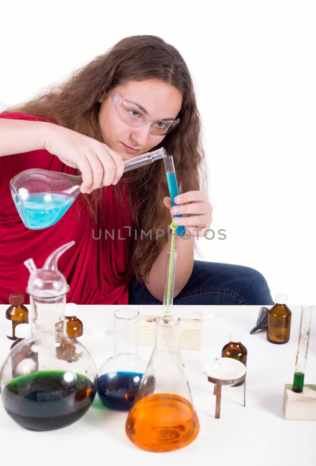 Portrait of school girl making chemical experiments with multicolored liquid in test tubes isolated over white background by aprilphoto