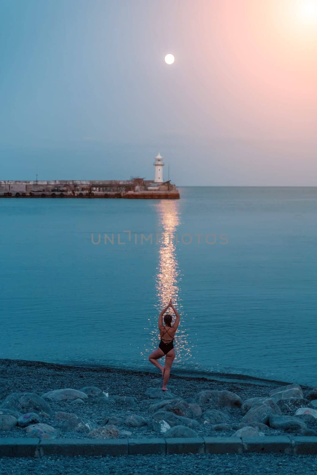 Full moon rises to the lighthouse, lunar path on the sea woman. by Matiunina