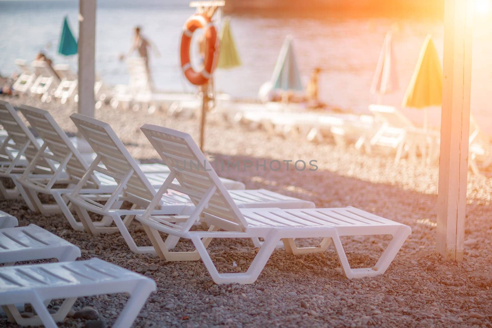 Several white sun loungers and an umbrella on the beach. The concept of a perfect vacation