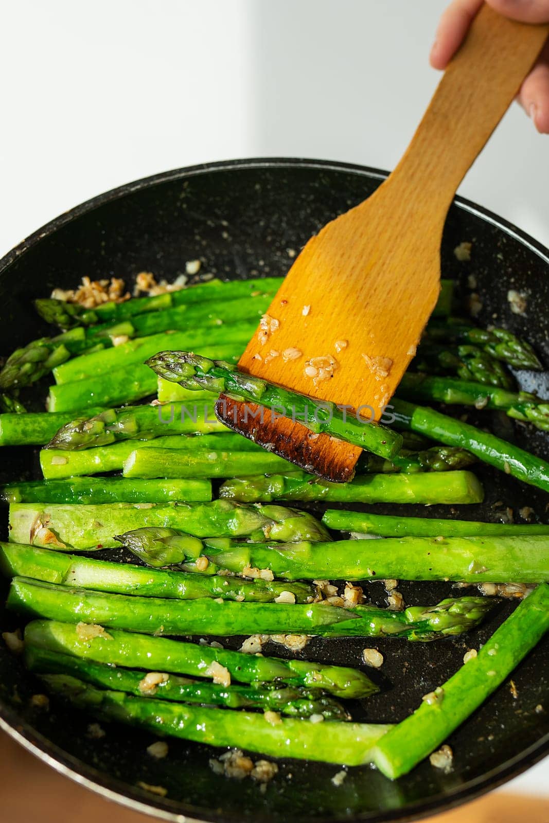 Close-up of healthy frying asparagus with salt and garlic in a frying pan. Delicious and healthy food