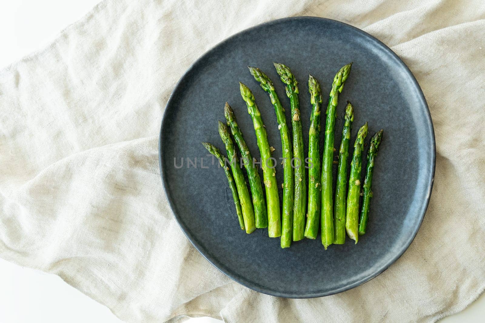 Close-up on a large plate - asparagus with salt and garlic. Delicious and healthy food, served in a restaurant, beautiful layout. by sfinks