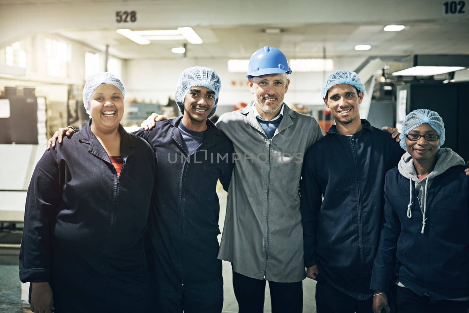 Were like a family in this company. Portrait of a manager standing arm in arm with his staff on a printing factory floor