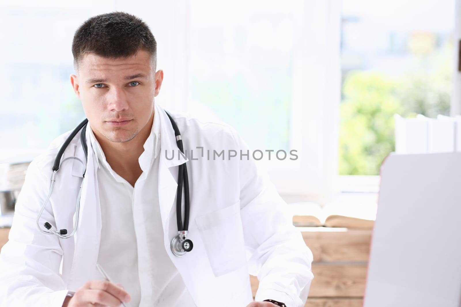 Handsome smiling male doctor sit at by kuprevich