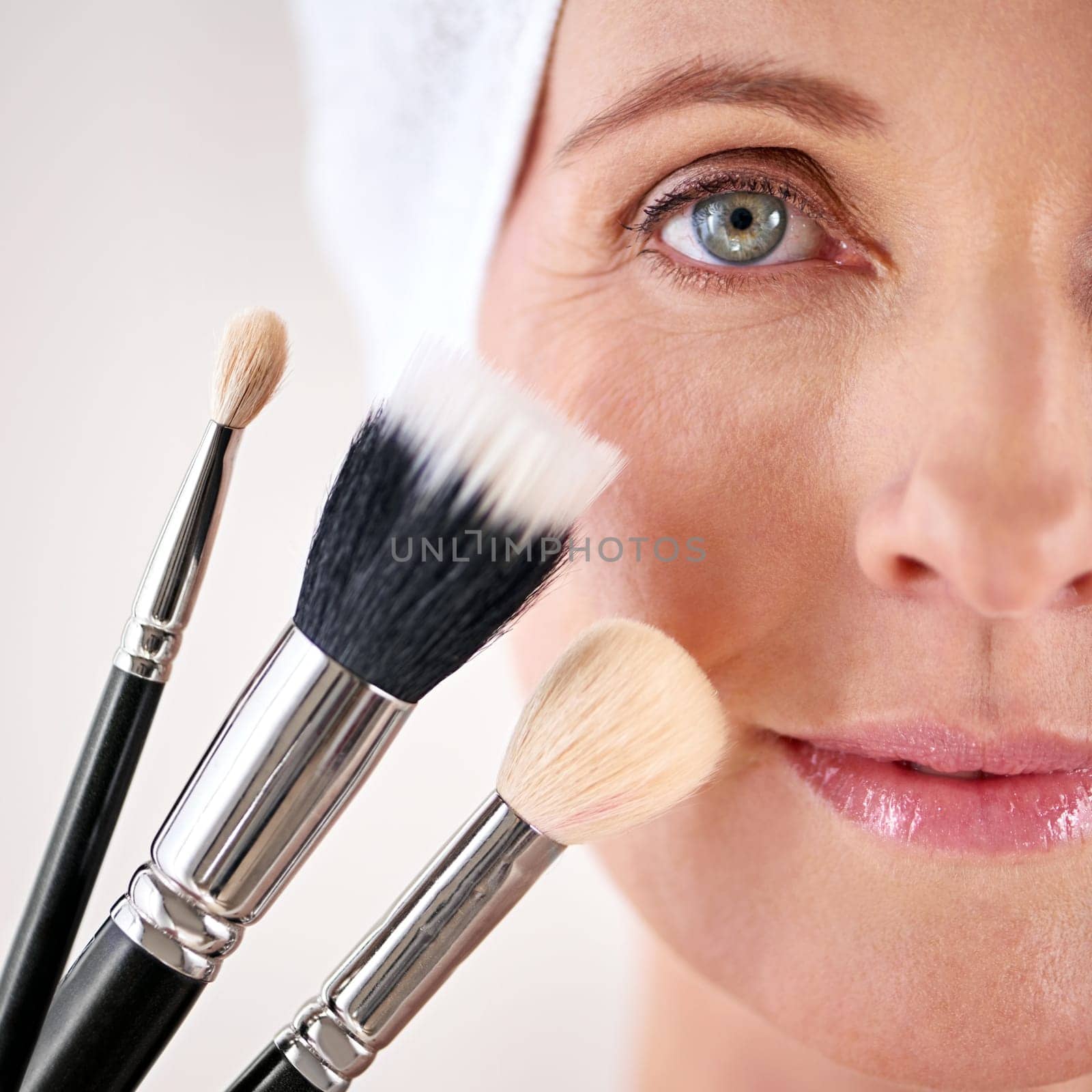 Beauty time. Closeup studio portrait of a mature woman posing with a set of makeup brushes. by YuriArcurs