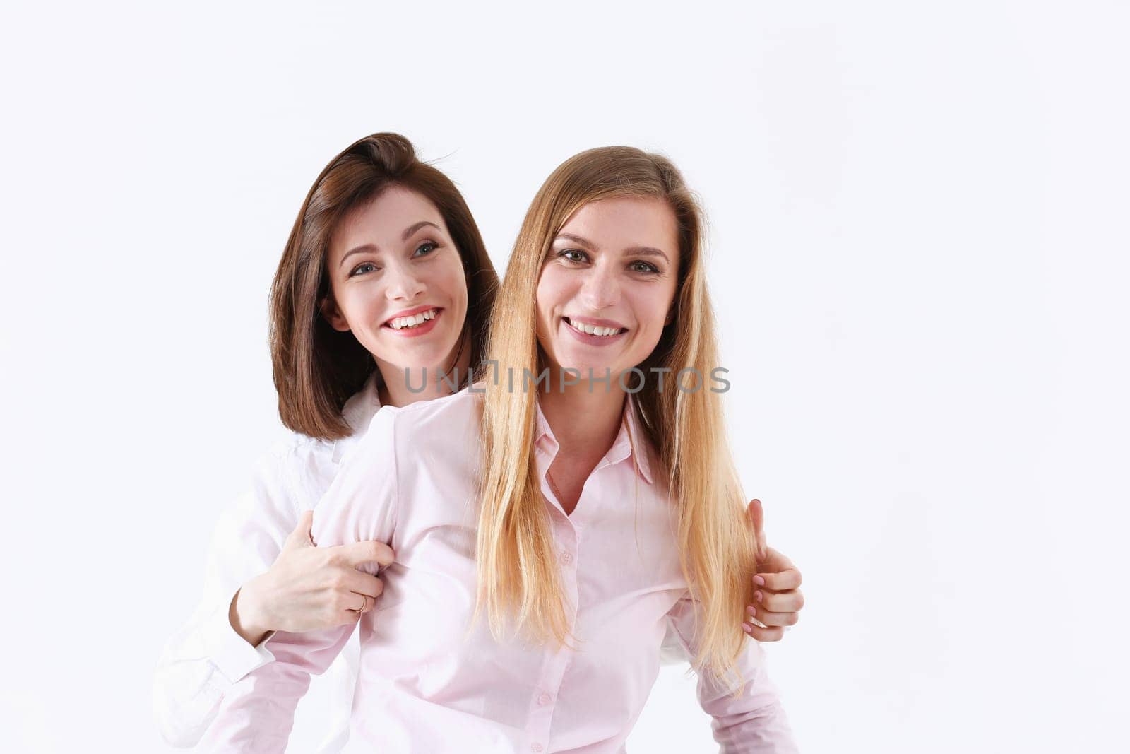 Two smiling happy joyful female friends portrait looking in camera over white background. Homosexual marriage lesbian couple love relations modern positive relationship concept