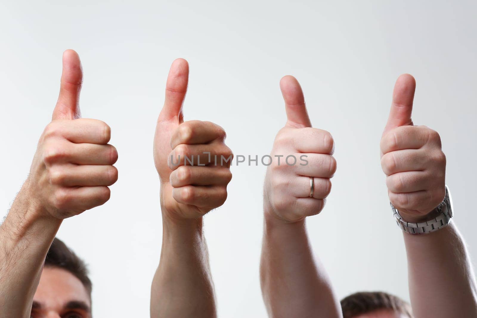 A group of people male hands on a gray background holds a thumb up expressing agreement finger OK concept is large closeup concept