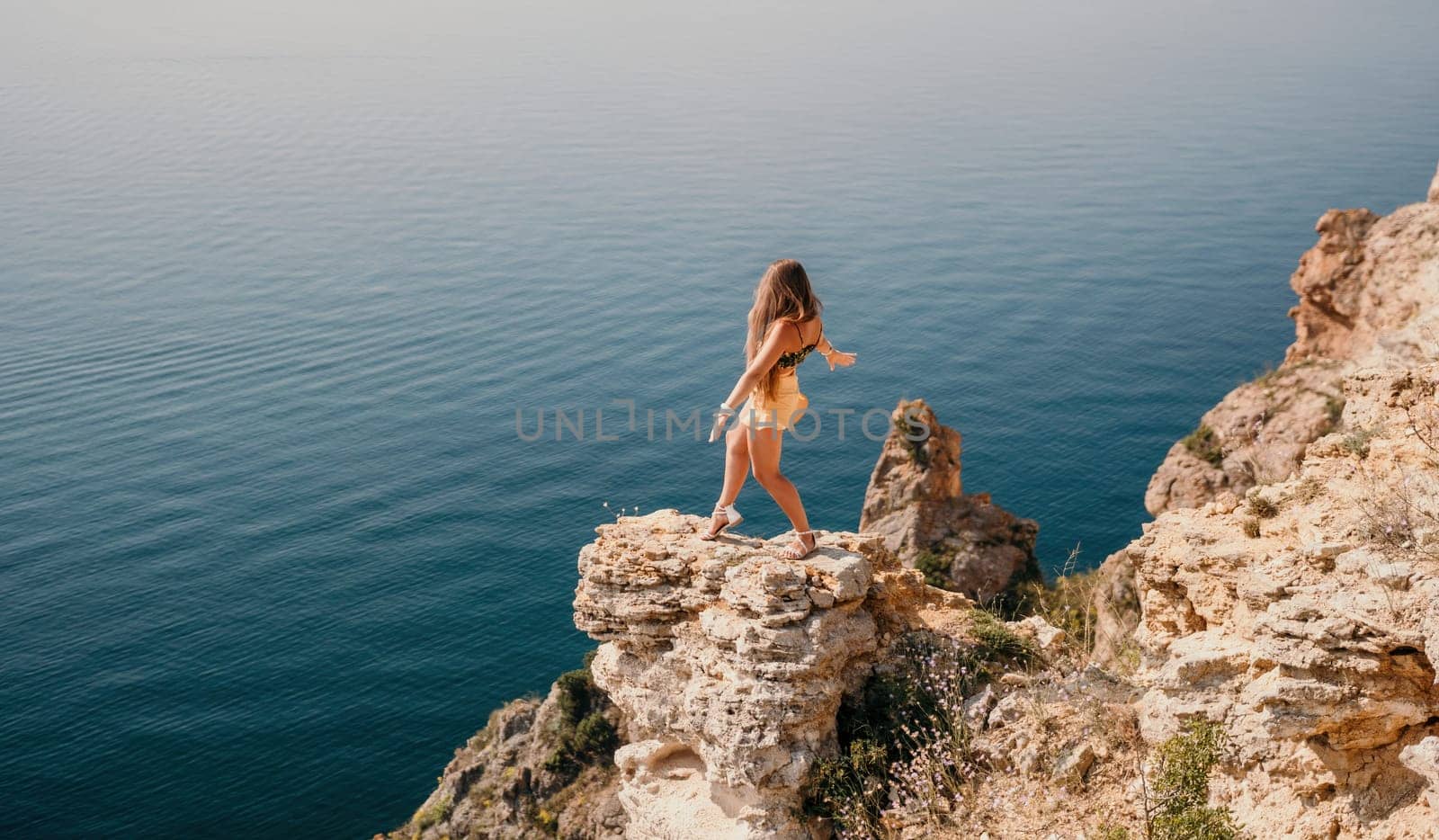 Woman travel sea. Happy tourist taking picture outdoors for memories. Woman traveler looks at the edge of the cliff on the sea bay of mountains, sharing travel adventure journey.