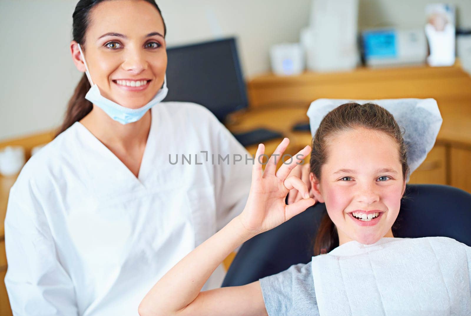 Another perfect checkup. Portrait of a young girl sitting in a dentists chair giving an ok sign. by YuriArcurs
