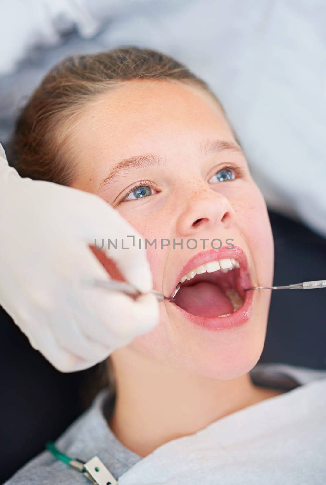 Her day at the dentist. Closeup shot of a young girl having a checkup at the dentist. by YuriArcurs